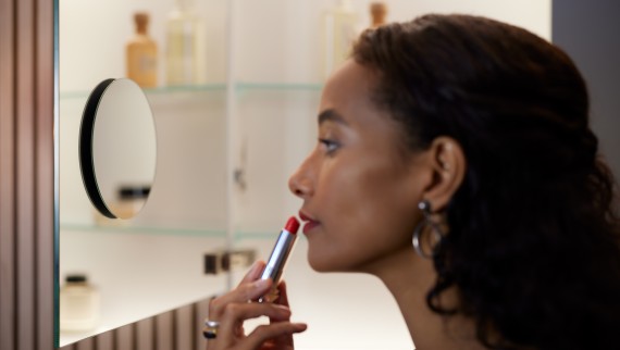 Femme se maquillant devant le miroir de la salle de bains Femme se maquillant devant le miroir de la salle de bains