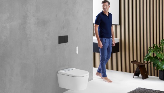 Homme admirant l'espace WC Geberit d'une salle de bains Homme admirant l'espace WC Geberit d'une salle de bains