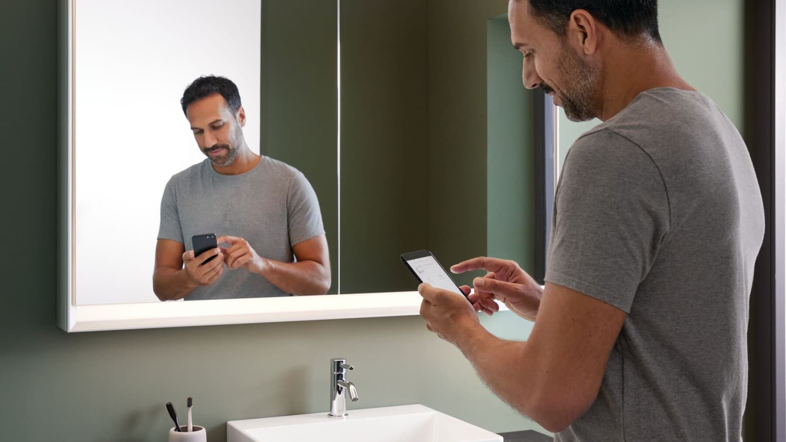 Homme debout dans la salle de bains avec un téléphone portable Homme debout dans la salle de bains avec un téléphone portable