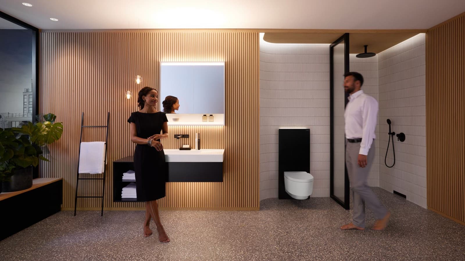 Homme et femme dans une salle de bains parfaitement éclairée avec les produits Geberit ONE Homme et femme dans une salle de bains parfaitement éclairée avec les produits Geberit ONE