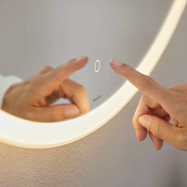 Interrupteur sensitif à commande manuelle sur le miroir Geberit Option Round (© Geberit) Interrupteur sensitif à commande manuelle sur le miroir Geberit Option Round (© Geberit)