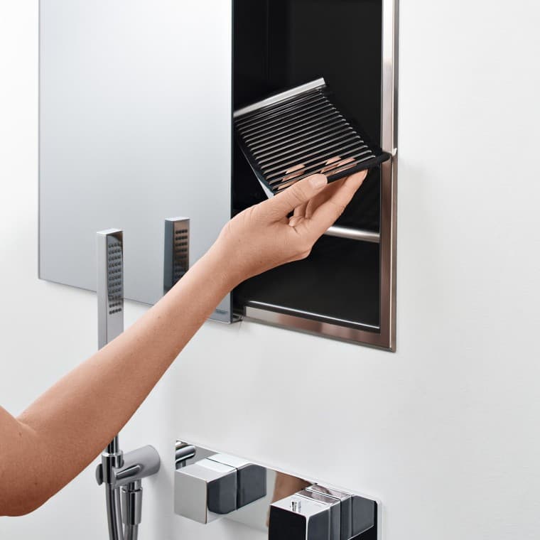 Hand van een vrouw die een inlegbodem in de nisaflegbox in de douche plaatst (© Geberit) Hand van een vrouw die een inlegbodem in de nisaflegbox in de douche plaatst (© Geberit)