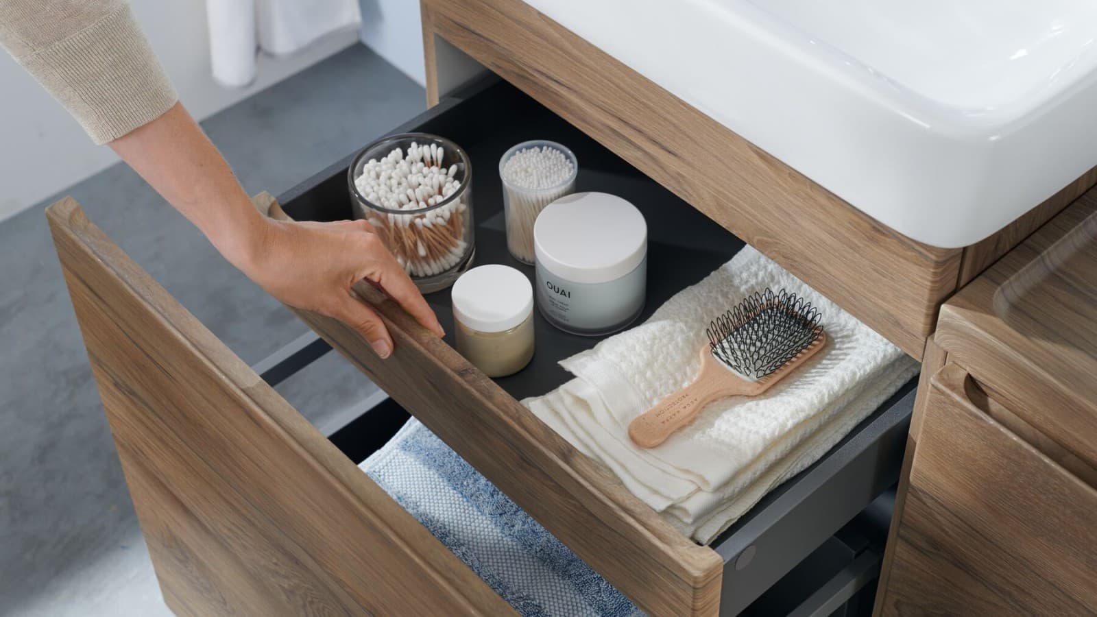 Une femme ouvre le meuble sous-lavabo Selnova plan de Geberit Une femme ouvre le meuble sous-lavabo Selnova plan de Geberit