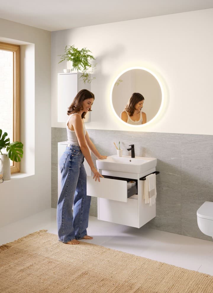 Femme dans une salle de bains blanche de la ligne Geberit Renova Plan Femme dans une salle de bains blanche de la ligne Geberit Renova Plan