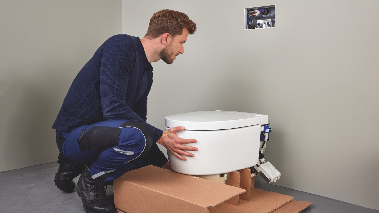 Un professionnel du sanitaire installe un WC lavant Geberit AquaClean Sela Un professionnel du sanitaire installe un WC lavant Geberit AquaClean Sela