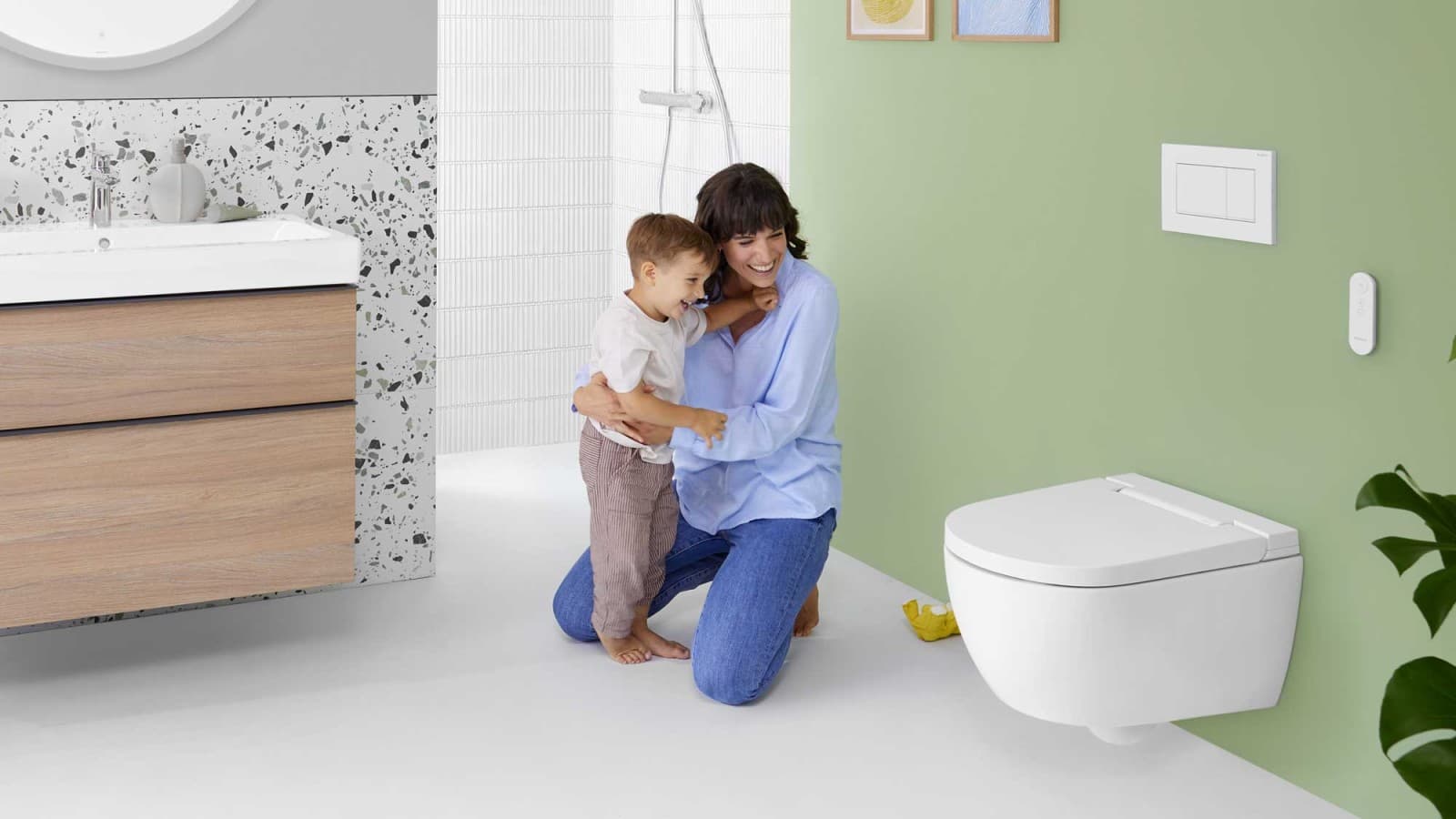 Une femme avec un enfant devant un WC-douche Geberit AquaClean Alba Une femme avec un enfant devant un WC-douche Geberit AquaClean Alba